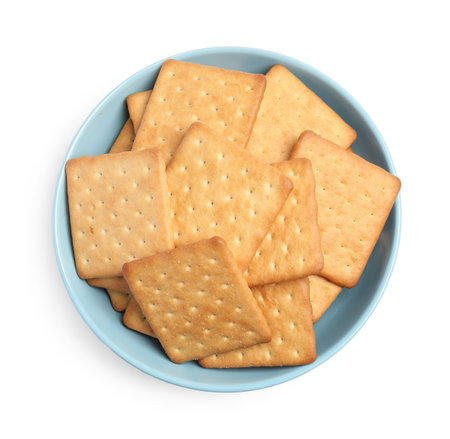 Tasty crackers in bowl isolated on white, top viewの写真素材