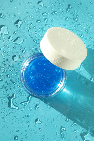Open jar of cosmetic product on wet turquoise background, top viewの写真素材