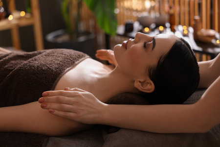 Spa therapy. Beautiful young woman lying on table during massage in salonの写真素材