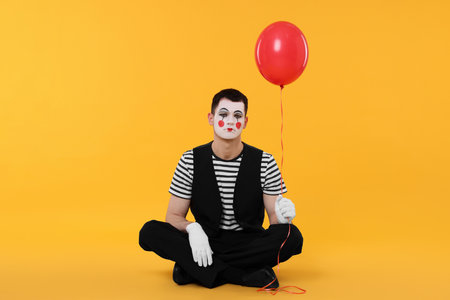 Funny mime artist with balloon on orange backgroundの写真素材