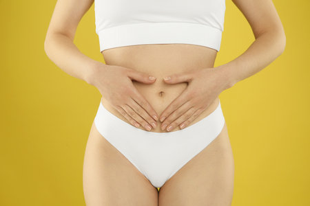 Gynecology. Woman in underwear on yellow background, closeup