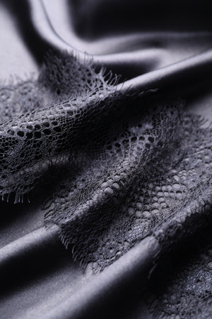Beautiful lace with pattern on black fabric, closeupの写真素材