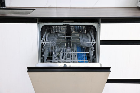 Built-in dishwasher with open door indoors. Home appliance