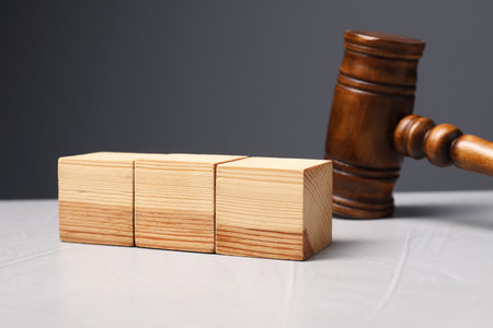Law. Blank wooden cubes and gavel on light table against gray backgroundの写真素材