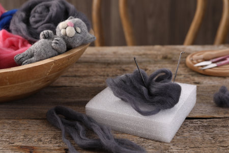 Felting tools, wool and toy cat on wooden tableの写真素材