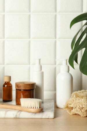 Different bath accessories and personal care products on wooden table near white tiled wallの写真素材