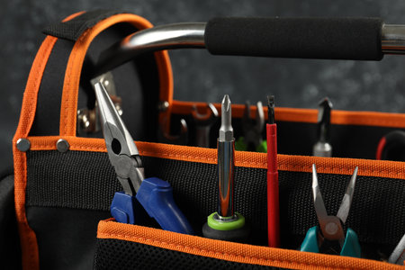 Bag with needle nose pliers, screwdrivers and other tools for repair on dark background, closeupの写真素材