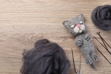 Felted cat, wool and tools on wooden table, flat lay. Space for textの写真素材