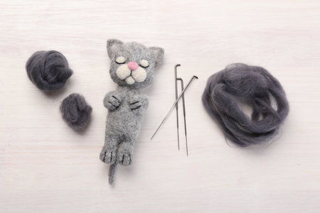 Felted cat, wool and needles on light wooden table, flat layの写真素材