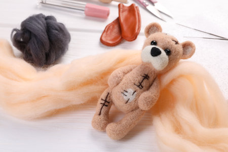 Felted bear, wool and tools on white wooden table, closeupの写真素材