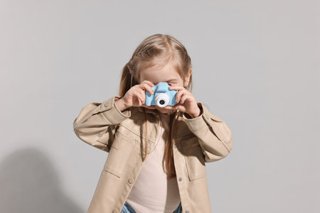 Fashion concept. Stylish girl with toy camera on light grey backgroundの写真素材