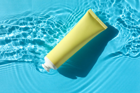 Tube with moisturizing cream in water on light blue background, top viewの写真素材