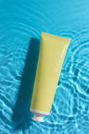 Tube with moisturizing cream in water on light blue background, top viewの写真素材