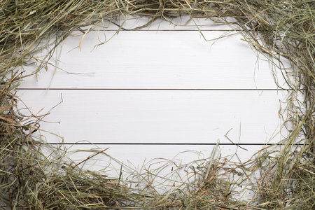 Frame made of dried hay on white wooden table, top view. Space for textの写真素材