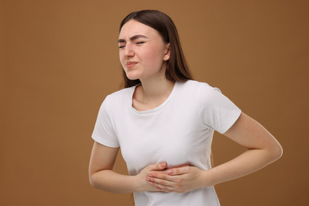 Woman having heart attack on brown backgroundの写真素材