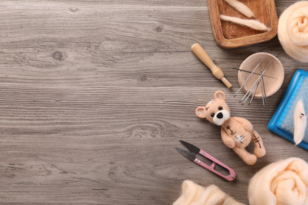 Felted bear, wool and different tools on wooden table, flat lay. Space for textの写真素材