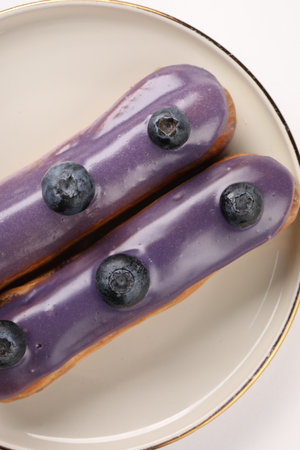 Delicious eclairs decorated with blueberries on white background, top viewの写真素材