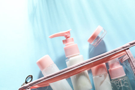 Cosmetic travel kit with plastic bag on light blue background, top view. Space for textの写真素材