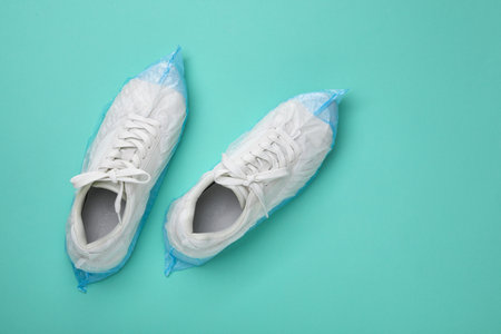 Sneakers in shoe covers on turquoise background, top view. Space for textの写真素材