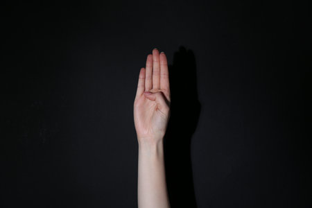 Woman showing open palm on black background, closeupの写真素材