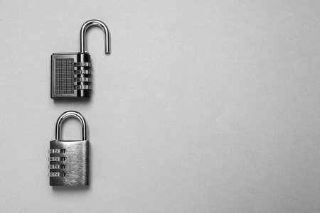 Steel combination padlocks on gray background, top view. Space for text