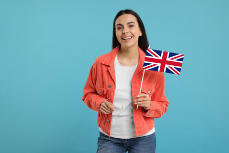 Happy young woman with flag of United Kingdom on light blue backgroundの写真素材