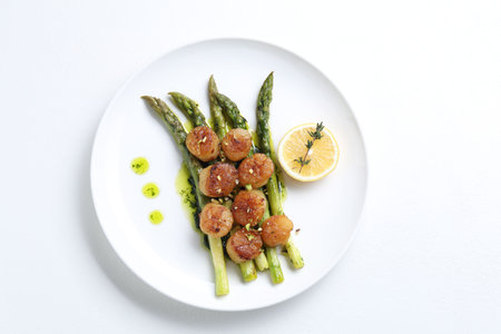 Delicious fried scallops with asparagus, lemon and thyme on white background, top viewの写真素材