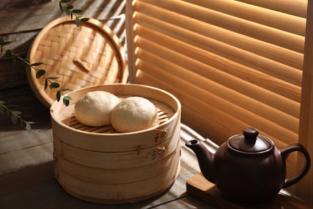Delicious Chinese steamed buns and kettle on wooden table, closeupの写真素材