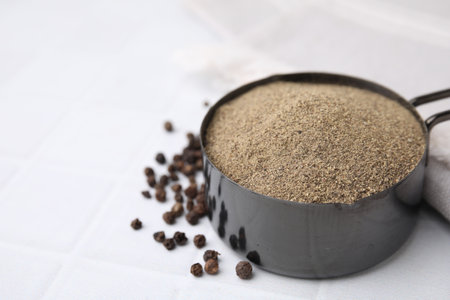 Ground pepper and peppercorns on white tiled table, closeup. Space for textの写真素材
