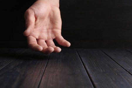 Man holding hand above black wooden table, closeup. Space for textの写真素材