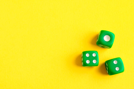 Three green game dices on yellow background, flat lay. Space for textの写真素材