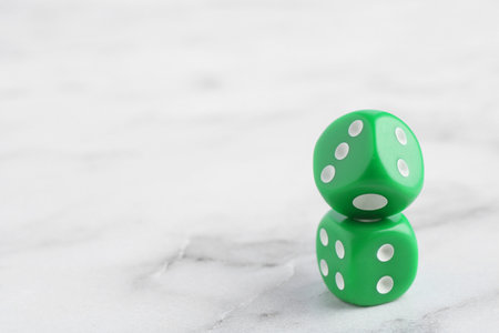 Two green game dices on white marble table, closeup. Space for textの写真素材