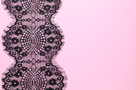 Black lace on pink background, top view. Space for textの写真素材