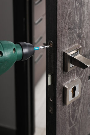 Repairing door handle with electric screwdriver indoors, closeupの写真素材