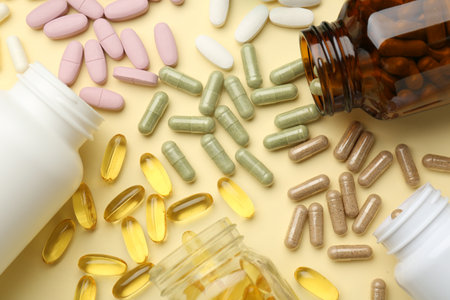 Many different vitamin pills and bottles on beige background, flat layの写真素材