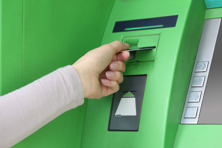 Woman inserting credit card into green cash machine, closeupの写真素材