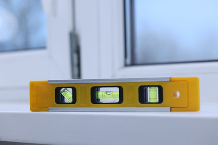 Yellow building level on white windowsill indoors