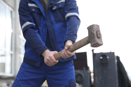 Man in uniform with sledgehammer outdoors, closeupの写真素材