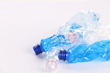 Crumpled disposable plastic bottles on white background, space for text