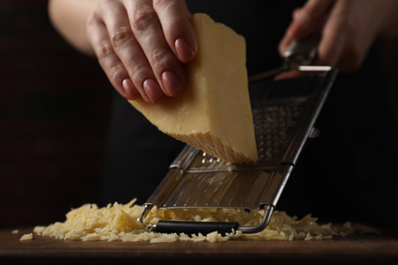 Woman grating cheese at wooden table, closeupの写真素材