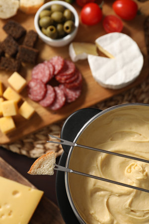 Fondue with tasty melted cheese, forks and different snacks on table, top viewの写真素材