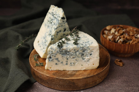 Tasty blue cheese with thyme and walnuts on brown table