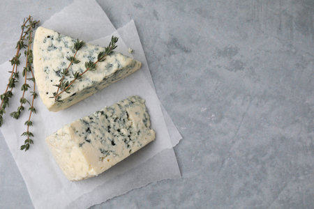 Tasty blue cheese with thyme on gray table, top view. Space for textの写真素材