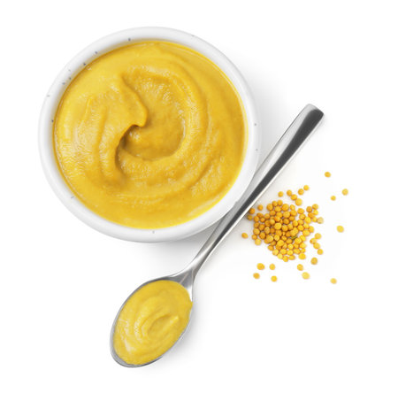 Fresh tasty mustard sauce in bowl and spoon with dry seeds isolated on white, top viewの写真素材