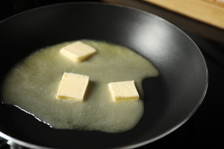 Melting butter in frying pan on black table, closeupの写真素材