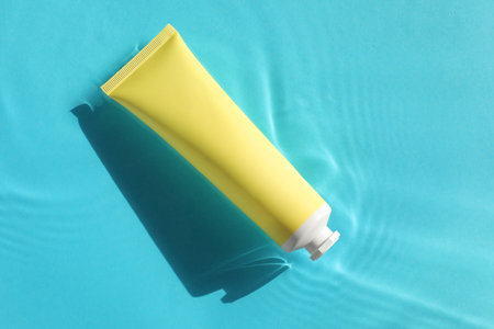 Tube with moisturizing cream in water on light blue background, top viewの写真素材