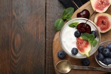 Glass with yogurt, berries and mint on wooden table, top view. Space for textの写真素材
