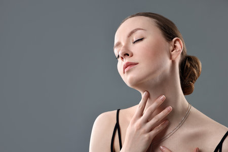 Fashionable portrait of beautiful young woman on grey backgroundの写真素材