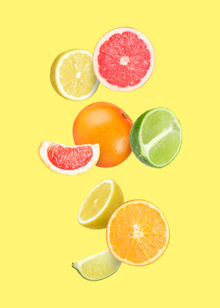 Many different fresh citrus fruits in air on light yellow backgroundの写真素材