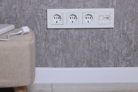 Electric power sockets on gray wall indoors, space for textの写真素材